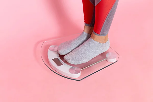 A women measuring weight on a scale.