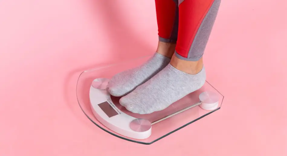 A women measuring weight on a scale.