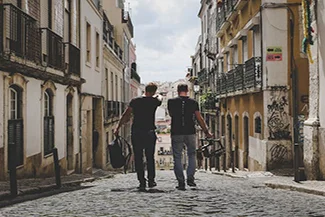 Two men stroll down a cobblestone street, embodying friendship and the joy of shared experiences in life.