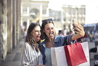 Two women smiling and taking a selfie with their cell phone, capturing a moment of friendship and joy together.