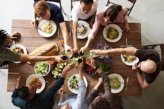  A diverse group of individuals gathered around a table filled with food, sharing laughter and meaningful conversations.