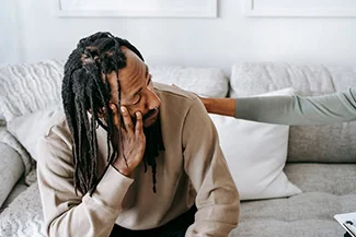 A man seated on a couch, illustrating the comfort of a caring friend during tough times.