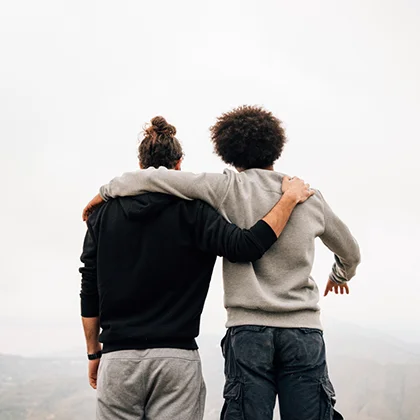 At the mountain summit, two men stand together, representing the invaluable gift of friendship in a stunning natural setting.