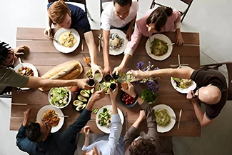 A diverse group of individuals gathered around a table filled with food, sharing laughter and meaningful conversations.
