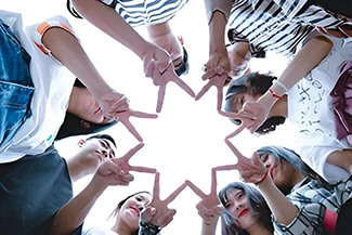 A diverse group of individuals forming a star shape with their hands, symbolizing unity and the power of friendship.