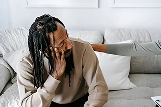 A man seated on a couch, illustrating the comfort of a caring friend during tough times.