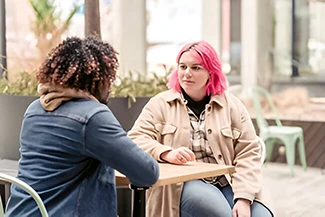 Two women engaged in conversation at a table, embodying the essence of true friendship and connection.