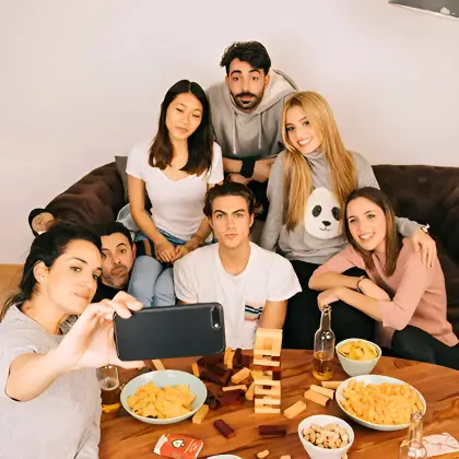 Friends play Jenga and snap a selfie mid-game—celebrating balance, laughter, and the joy of rising together.