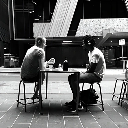 Two men at a city table, illustrating the essence of true friendship through generosity without expectations.