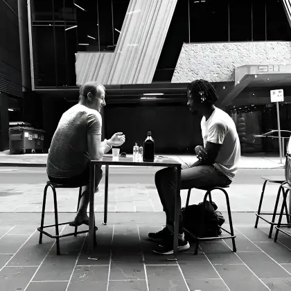 Two men at a city table, illustrating the essence of true friendship through generosity without expectations.