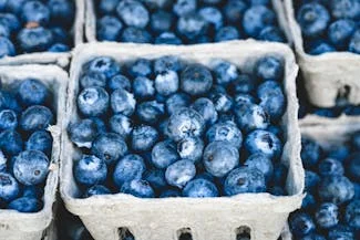 Fresh blueberries in baskets displayed at a vibrant farmers market, showcasing their rich color and natural appeal.