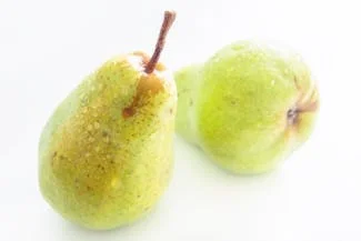 Two green pears placed against a stark white background, emphasizing their glossy texture and simple elegance.