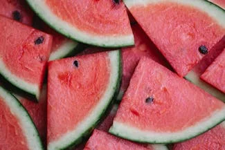 A vibrant pile of watermelon slices, showcasing their juicy red flesh and green rind, inviting a refreshing summer treat.