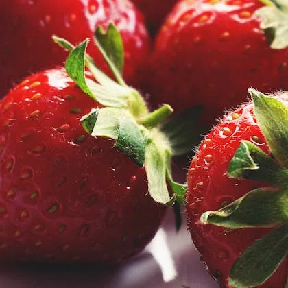 Detailed close-up of a bunch of strawberries, highlighting their juicy texture and bright red hue against a soft background.