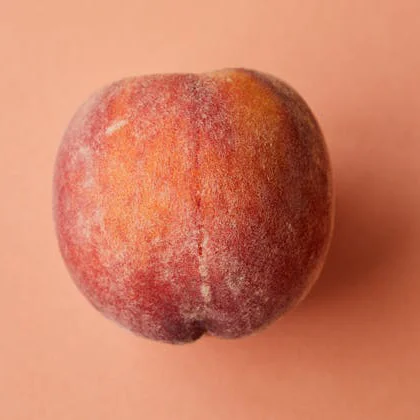 A solitary peach rests on a soft pink background, showcasing its vibrant color and smooth texture.