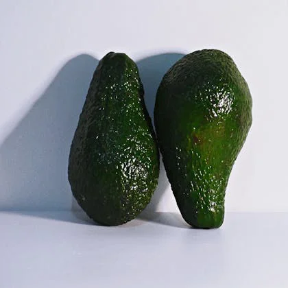 A pair of fresh avocados placed on a white background, highlighting their vibrant green color and unique texture.