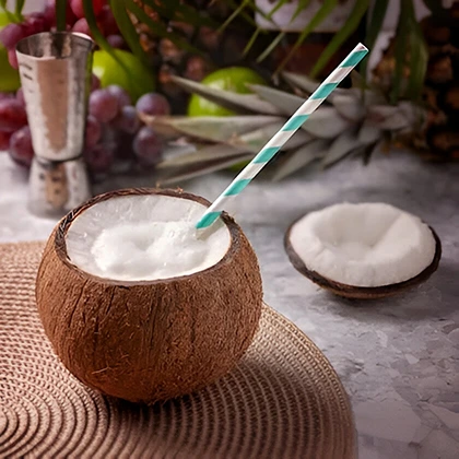 A refreshing coconut drink with a straw and tropical fruit placed on a wooden table, inviting and vibrant.