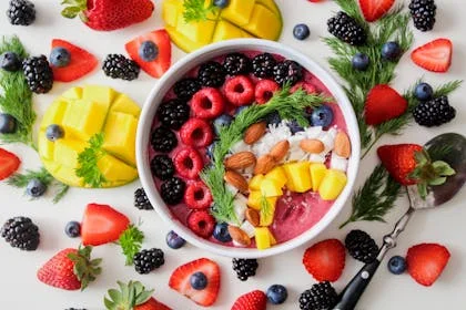 A colorful bowl of fresh fruits and berries with a spoon, representing a healthy breakfast that energizes your day.