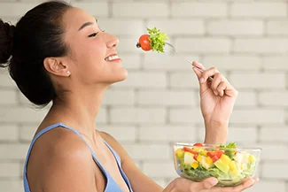 A woman with a fork and salad highlights the importance of mindful eating for enhanced enjoyment and reduced portions.