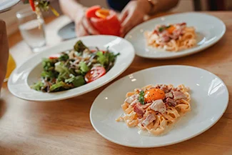 Two servings of balanced meals displayed on a wooden table, emphasizing the importance of portion control for health.