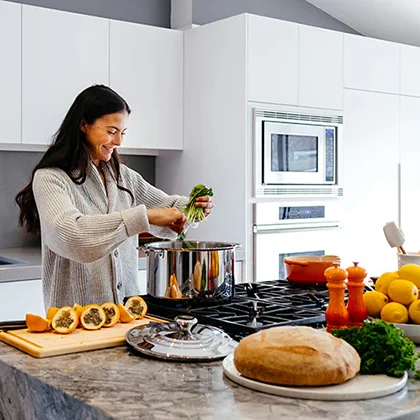 A woman is engaged in food preparation in a kitchen, emphasizing the health benefits of cooking at home with fresh ingredients.