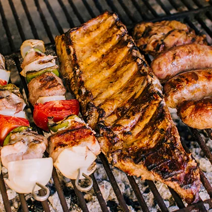 A grill filled with assorted meats and vegetables, showcasing a healthier cooking method compared to frying.