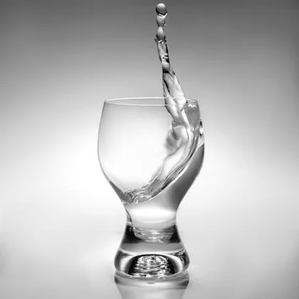 A glass of water with splashes, illustrating the importance of staying hydrated for optimal body function.