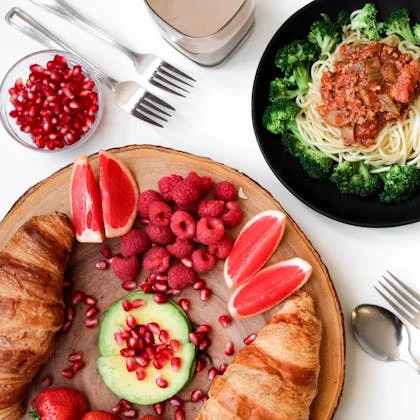 A vibrant assortment of fruit, vegetables, and a croissant on a plate, highlighting the importance of diverse nutrition.