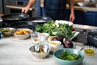 A man lovingly prepares food in a kitchen filled with various pans and bowls, embodying the joy of home cooking.