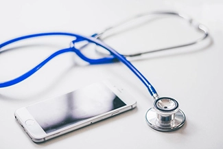 A mobile phone and stethoscope displayed together, representing the significance of routine check-ups for maintaining health.