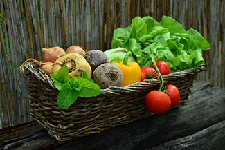 A rustic wooden table displays a basket overflowing with colorful vegetables, highlighting their role as nature's medicine