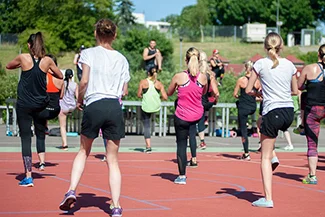 A diverse group of individuals engages in a dynamic workout session on a basketball court, celebrating their physical abilities.