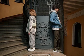 Two individuals standing on a staircase in front of an elevator, promoting the message: 'Take the stairs, not the elevator.'