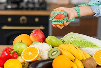 A person measures a colorful assortment of fruits and vegetables, emphasizing the importance of nourishing the body with healthy food.