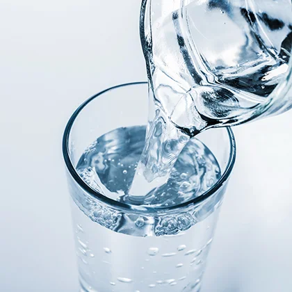  A glass is filled with water being poured, illustrating the necessity of drinking water for proper body function.