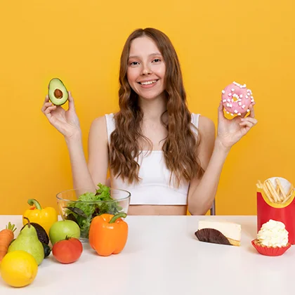 A woman presents two donuts and an avocado, illustrating the harmony of enjoying treats while prioritizing health.