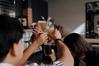 Friends raising their glasses in a toast at a bar, enjoying the moment while considering the health effects of excessive drinking.