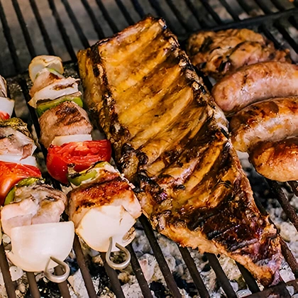 A grill filled with assorted meats and vegetables, showcasing a healthier cooking method compared to frying.