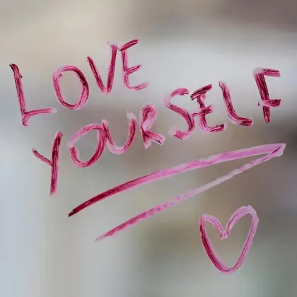 'LOVE YOURSELF' in pink lipstick and a heart adorn a mirror—an empowering reflection of self-acceptance and body love.