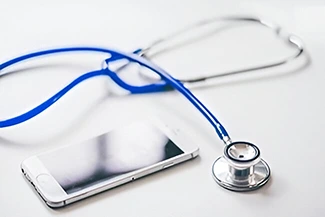 A mobile phone and stethoscope displayed together, representing the significance of routine check-ups for maintaining health.