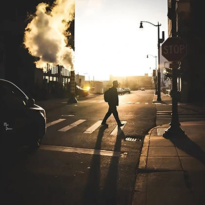 An individual walks across the street beside a stop sign, illustrating how a brief stroll can uplift one's entire day.