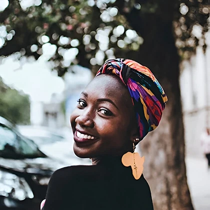 A joyful woman adorned with a colorful headscarf and earrings, exemplifying the stress-relieving benefits of laughter.