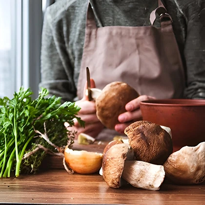 A person prepares mushrooms on a table, showcasing the dedication to healthy cooking and thoughtful meal preparation.