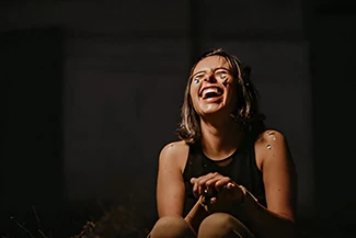 A woman laughs while sitting on the ground, her joy lighting up the moment and brightening the day.