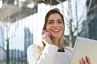 A professional woman in a business suit holds a tablet, her smile radiating positivity and confidence in the workplace.