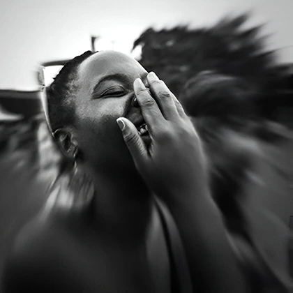 A woman joyfully laughs, holding her face, embodying the uplifting spirit of laughter as the best medicine for the soul.