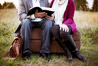 A couple reads a book on a couch, emphasizing the importance of relationship check-ins and shared moments.