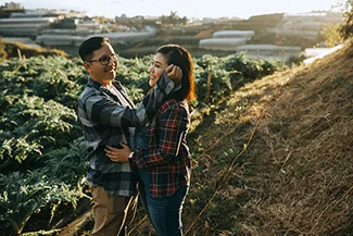 A couple stands together in a field at sunset, capturing their engagement while emphasizing the importance of communication.