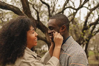 A young couple embraces in a park, symbolizing unconditional love and cherishing every moment spent together.