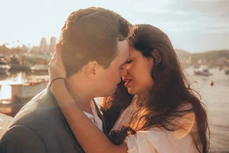 A couple embraces tenderly by the water, symbolizing love and the importance of small romantic gestures.